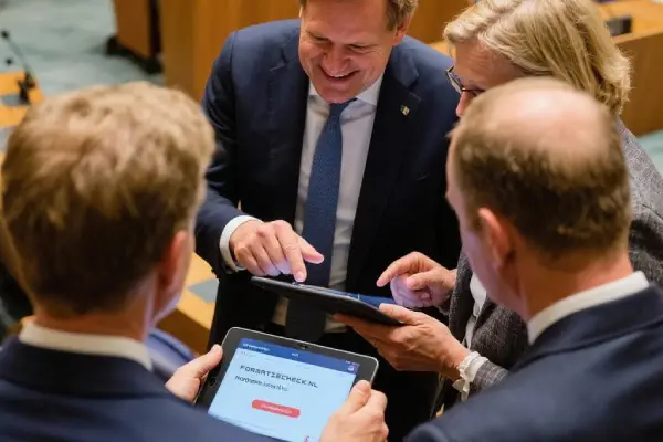 Leden van de tweede kamer bekijken de formatiecheck op tablet en bespreken de coalitie analyses